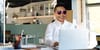 my smiling head with heart-shaped sunglasses superimposed on a person's body who is at a laptop in an office