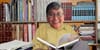 my smiling head superimposed on an eldery person's body who is reading a book in front of a full bookshelf